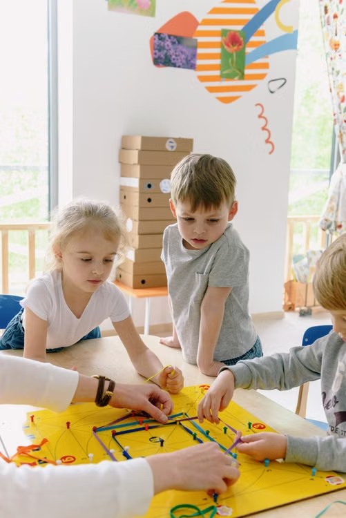 Children and teacher working together on a colorful geoboard activity